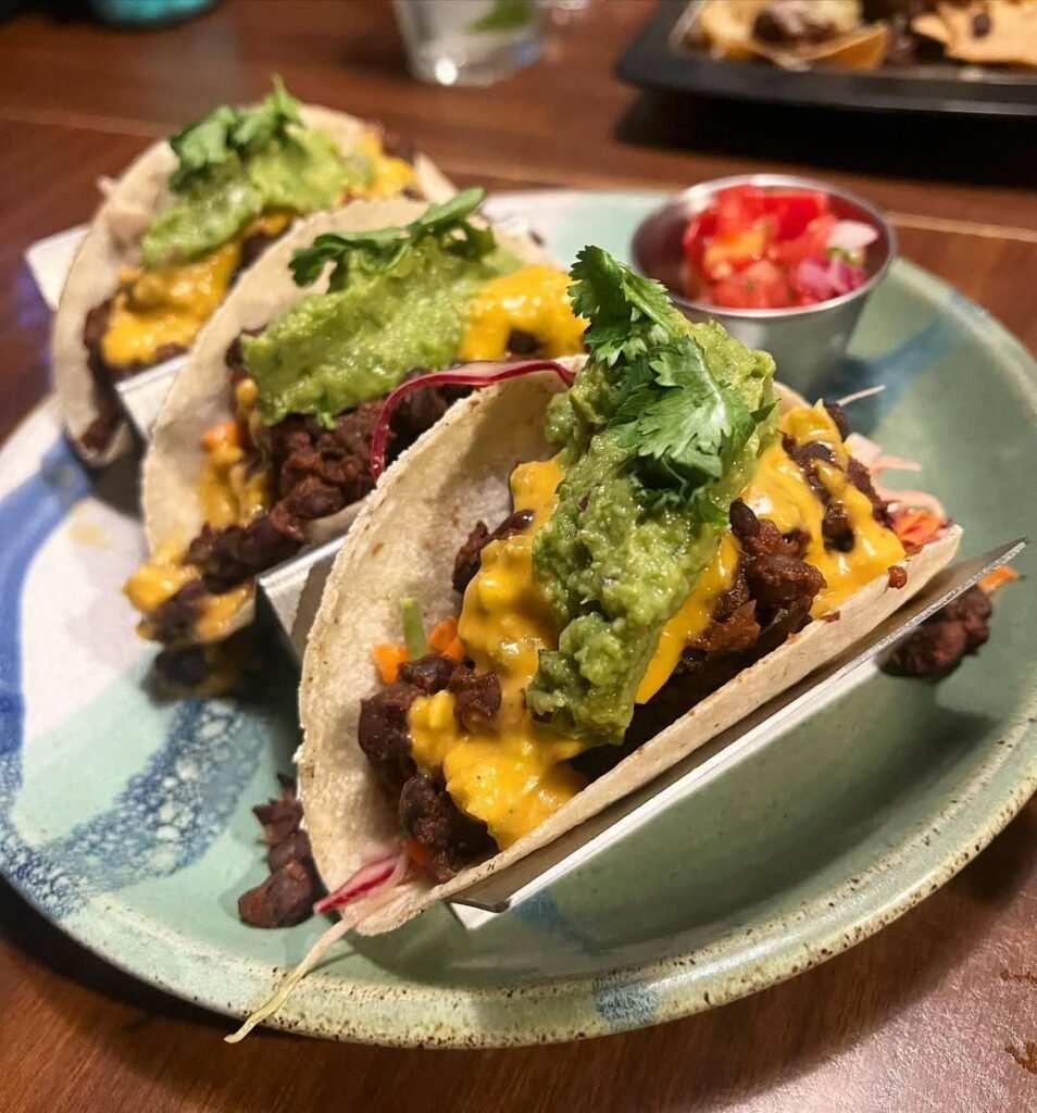 Spicy black bean tacos with avocado and tomatoes on a wooden table