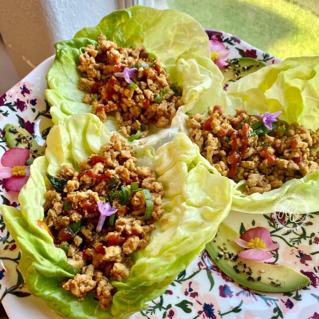 Herbed ground chicken lettuce wraps with colorful vegetables and sauce