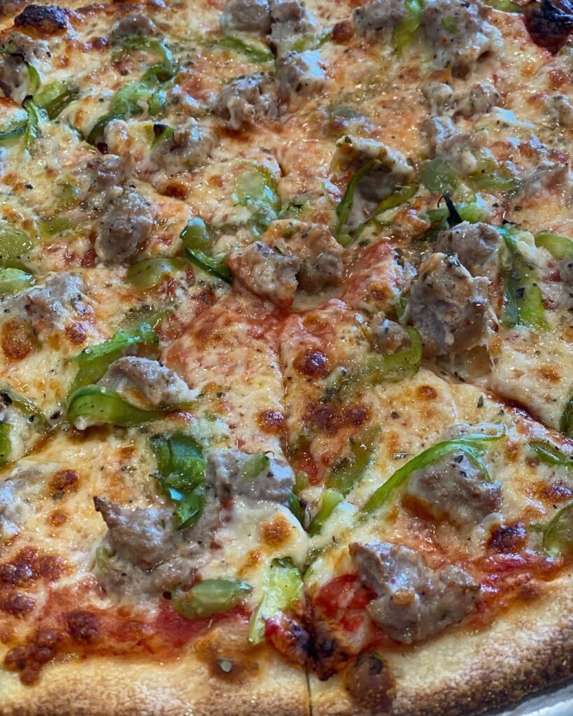 13 Easy And Delicious Grandma Pizza Recipes You Need To Try 8 A delicious sausage and peppers pizza on a wooden board.