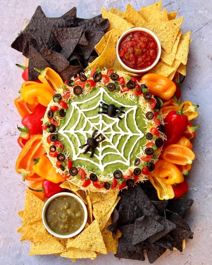 9 Best Halloween Party Treats Sure To Spook Your Guests 6 A spooky spider web dip with tortilla chips arranged around it, featuring a web design made of sour cream.
