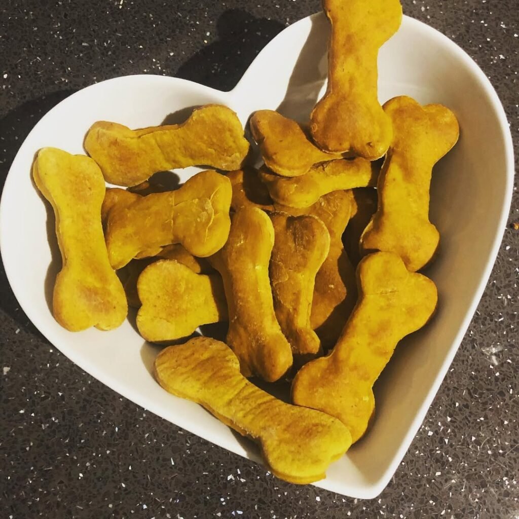 Peanut butter and pumpkin biscuits shaped like dog bones on a baking tray