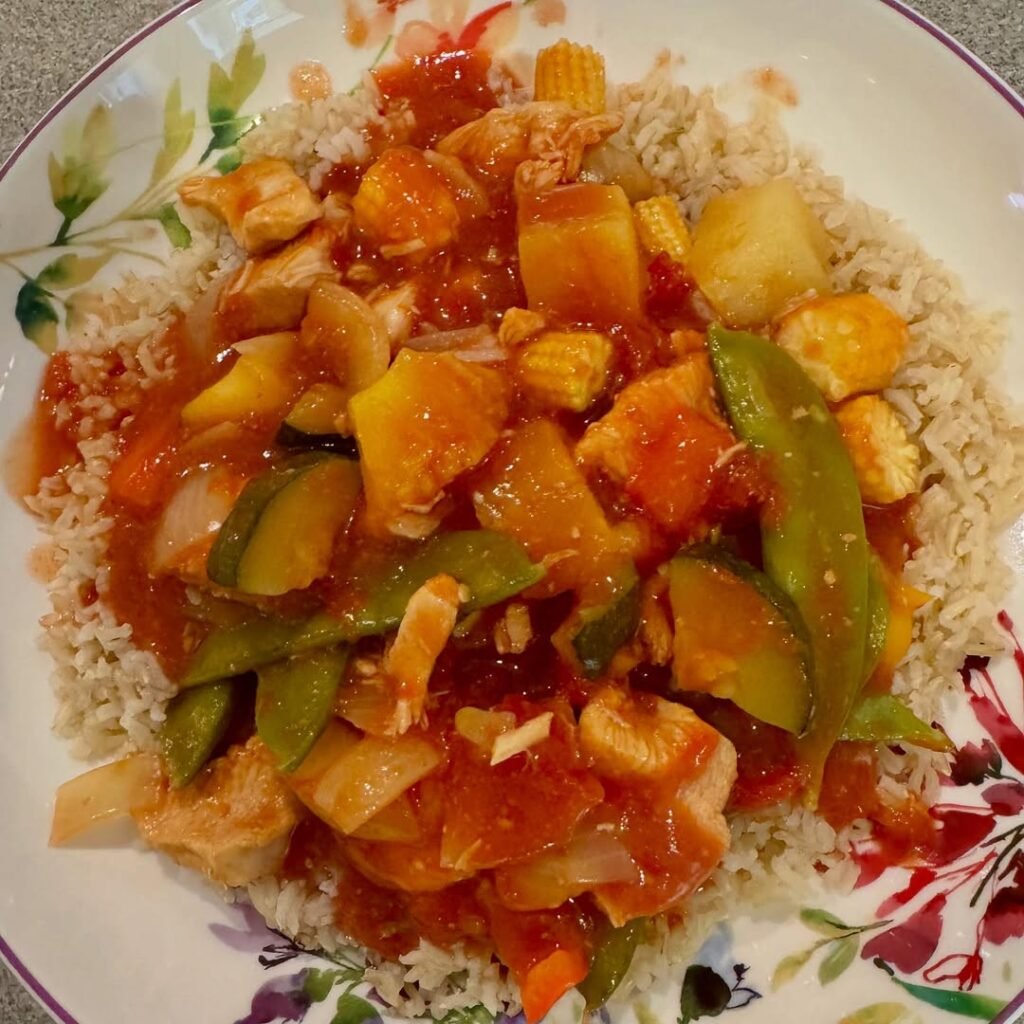 4 Chinese Sweet And Sour Chicken Recipes 5 A slow cooker filled with sweet and sour chicken, colorful vegetables, and pineapple chunks.