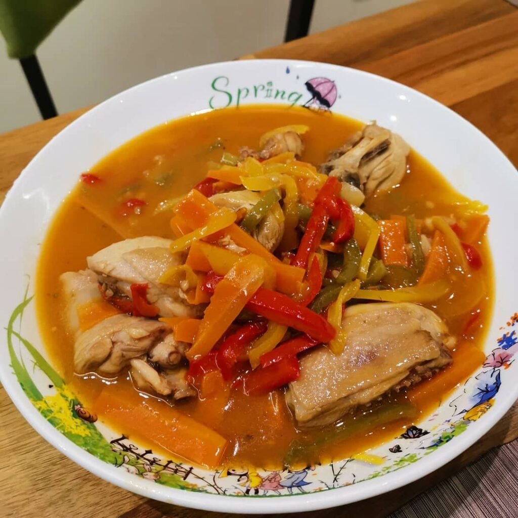 4 Chinese Sweet And Sour Chicken Recipes 3 Baked Sweet and Sour Chicken with colorful bell peppers in a bowl, garnished with fresh herbs.