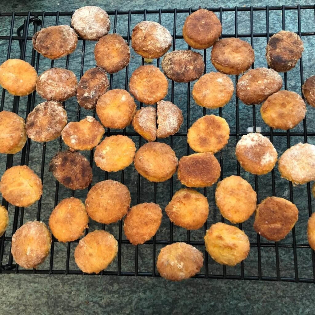 Carrot and apple dog treats on a cooling rack with fresh carrots and apples.
