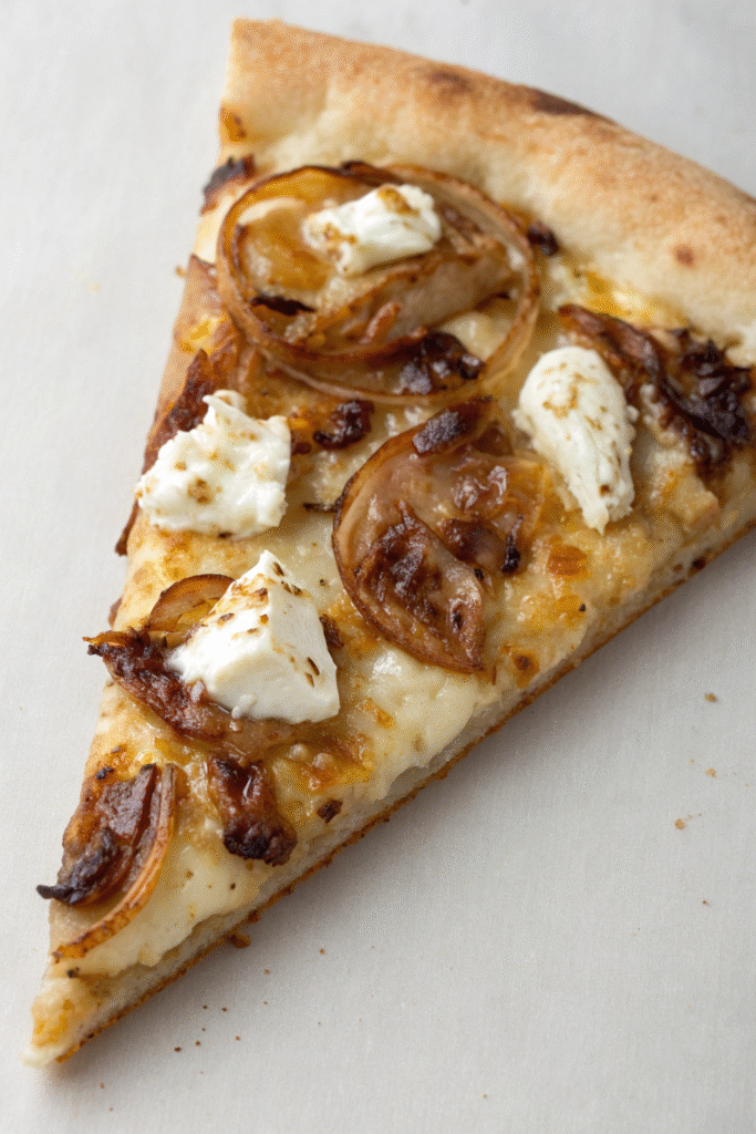 A pizza topped with caramelized onions and goat cheese ready to be baked.