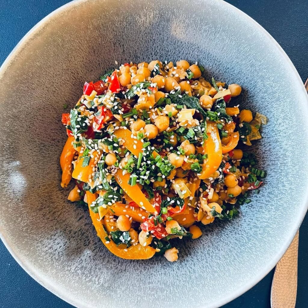A colorful chickpea stir-fry with bell peppers and onions in a skillet.