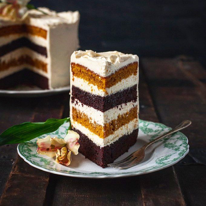 A slice of chocolate pumpkin cake on a decorative plate, surrounded by autumn leaves and small pumpkins.