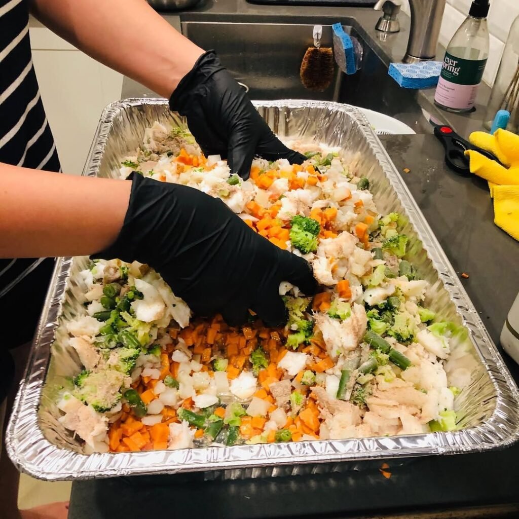 A plate of fish and sweet potatoes, with a dog in the background.