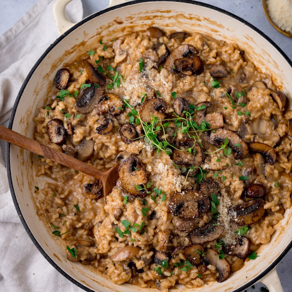 A bowl of creamy chicken and mushroom risotto with orzo pasta, garnished with parsley.