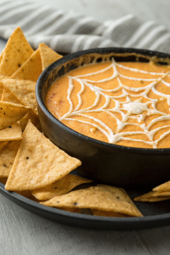 7 Best Spooky Halloween Party Appetizers 8 A spooky spider web cheese dip surrounded by tortilla chips and small pumpkins.