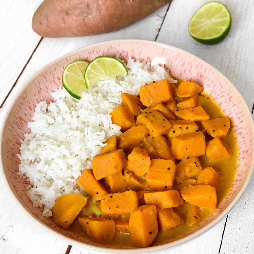 A bowl of vegetable curry with coconut milk served with rice, garnished with cilantro.