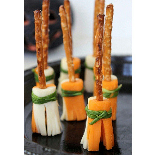 7 Best Spooky Halloween Party Appetizers 2 Witch's broomstick snacks made with pretzel rods and cheese, decorated with herbs.
