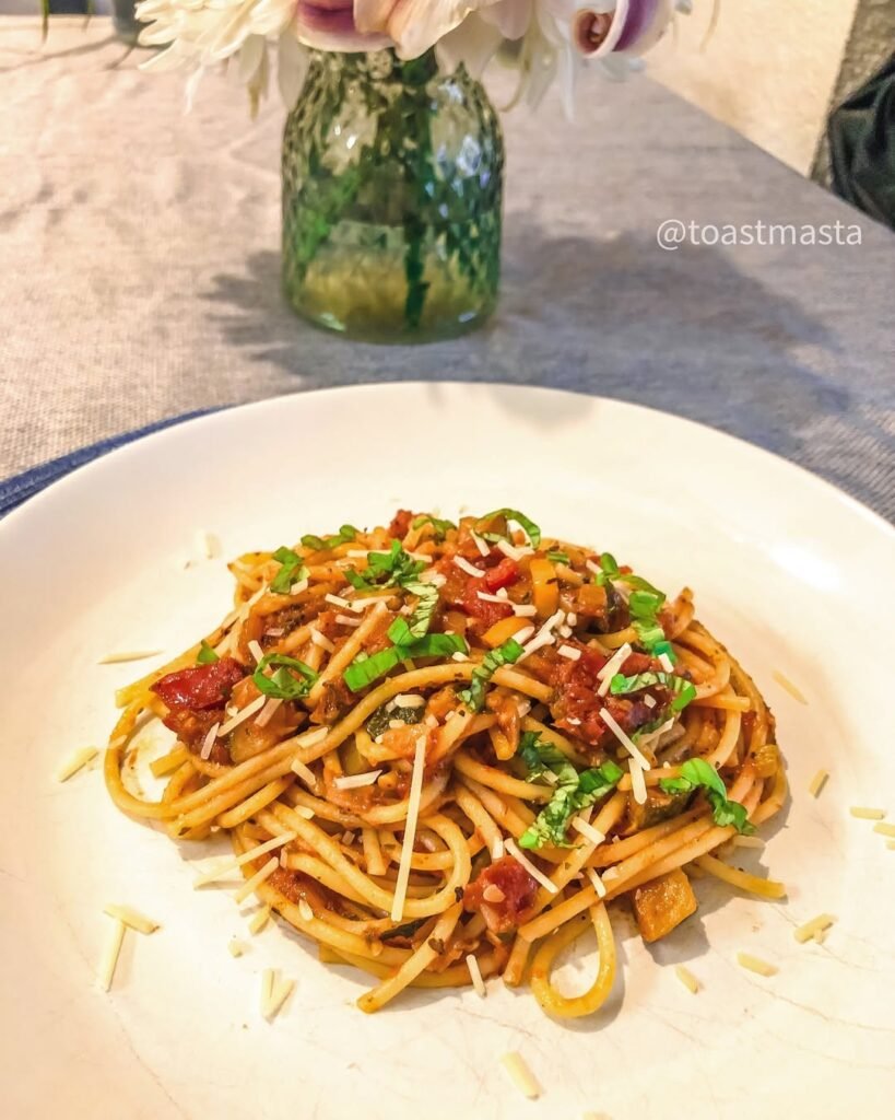A plate of zucchini noodles topped with marinara sauce and fresh basil leaves.