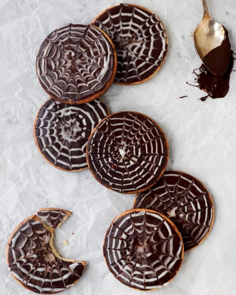 12 Best Halloween Desserts 7 Spooky Spiderweb Cupcakes decorated with black frosting and plastic spiders on a Halloween-themed table