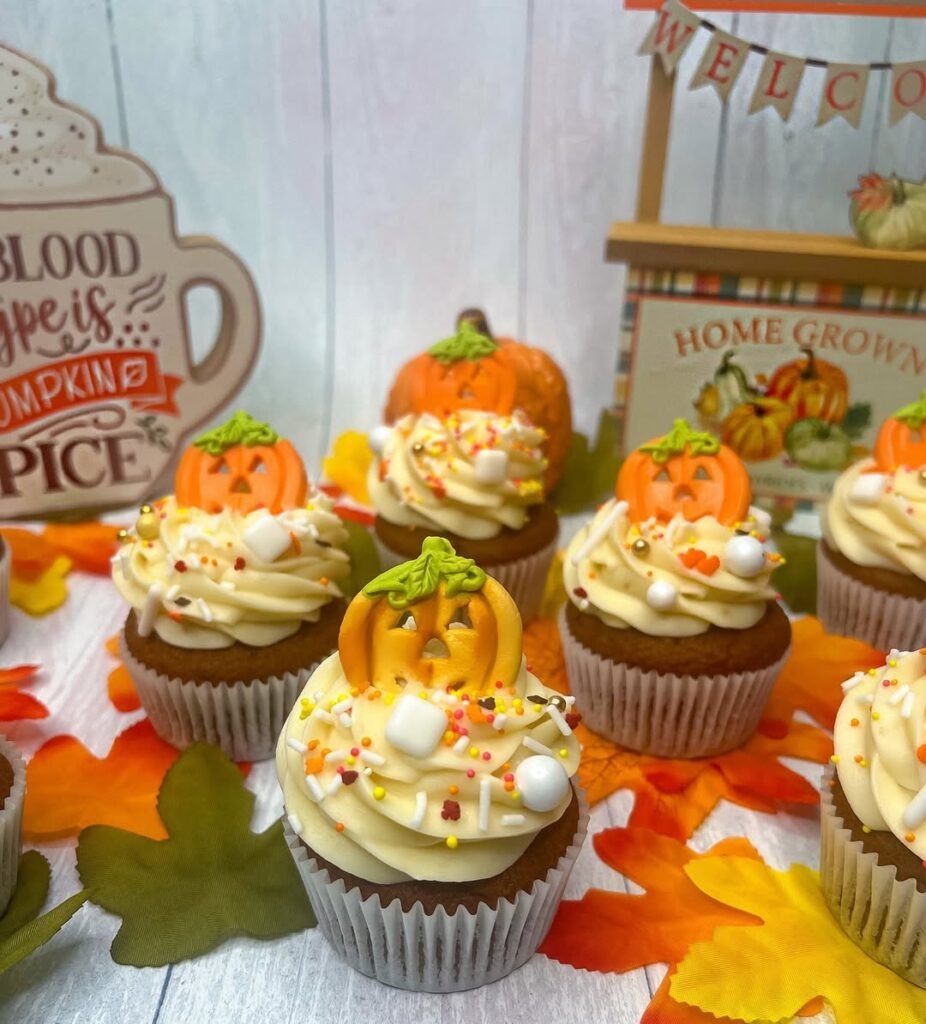 9 Best Halloween Party Treats Sure To Spook Your Guests 8 Pumpkin spice cupcakes with orange frosting and mini pumpkins on a decorative stand.