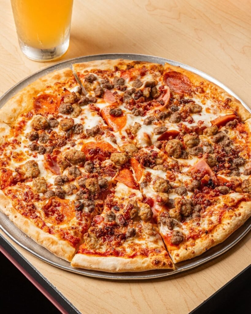 A delicious Meat Lovers' Supreme pizza topped with various meats and fresh basil.