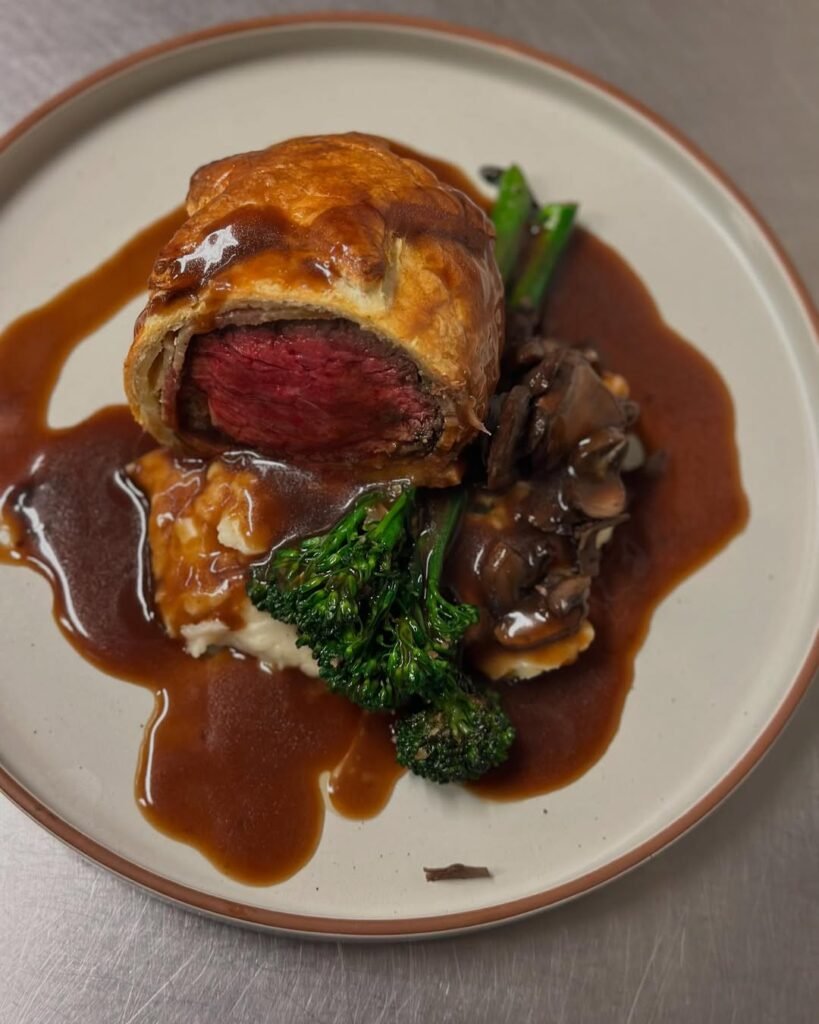12 Delicious Birthday Dinner Recipes You’ll Love 5 A beautifully cooked Beef Wellington with a rich red wine sauce, showcasing the tender beef and mushroom filling.