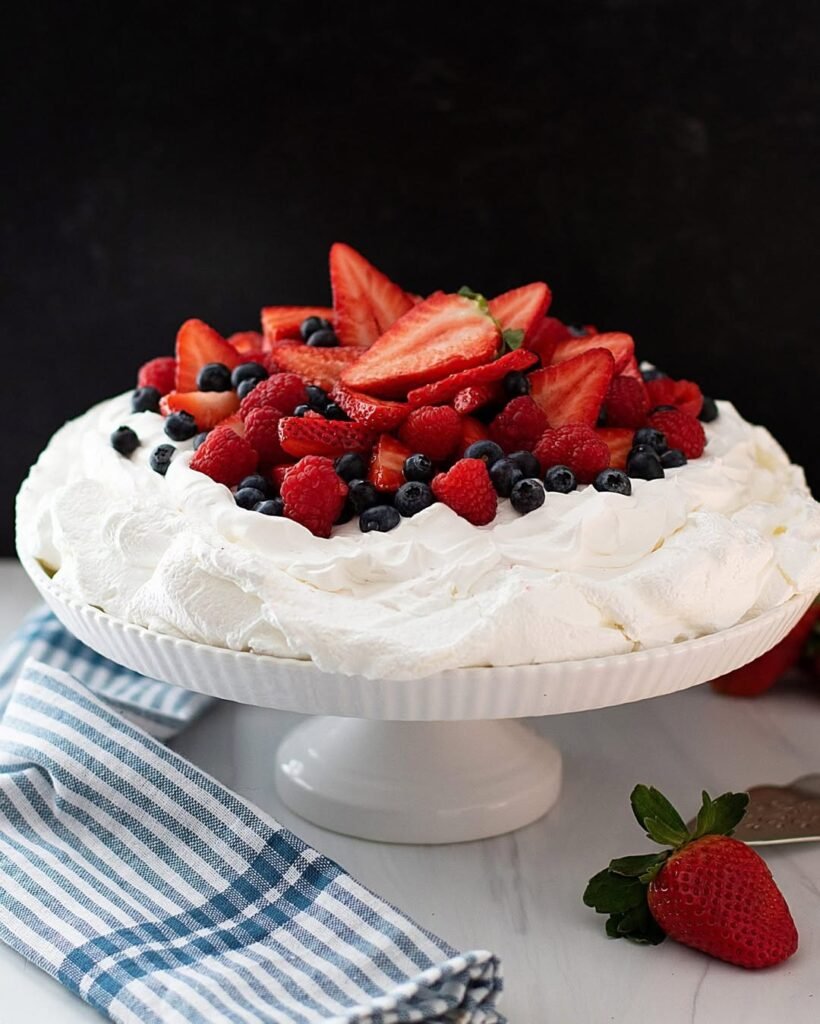 12 Delicious Birthday Dinner Recipes You’ll Love 11 A beautiful pavlova topped with whipped cream and a variety of fresh berries.