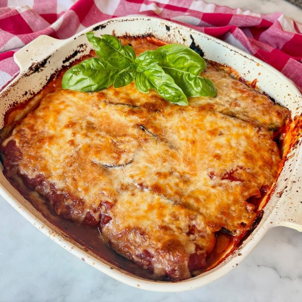 A delicious serving of eggplant parmesan topped with fresh basil on a wooden table.