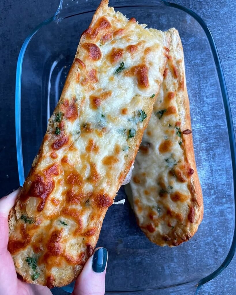 Cheesy garlic breadsticks served with marinara sauce on a wooden board.