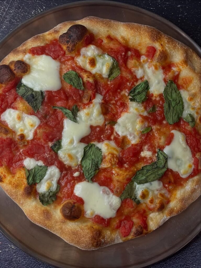 A delicious Margherita focaccia topped with fresh basil, tomatoes, and mozzarella.