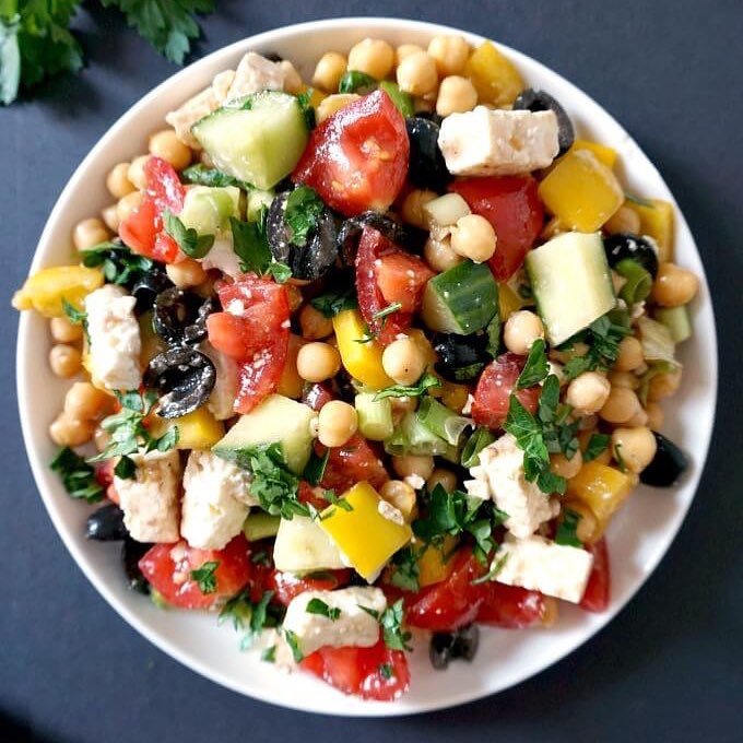 A bowl of creamy cauliflower soup garnished with chives and a drizzle of olive oil, served with slices of bread.