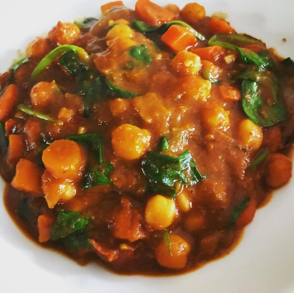 A bowl of Moroccan Chickpea Stew with spinach and a slice of bread