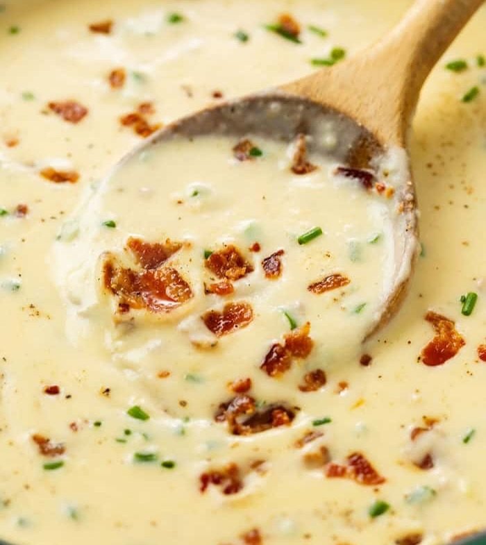12 Creamy Potato Soup Recipes to Warm Your Soul 2 A bowl of loaded baked potato soup topped with cheese, bacon, and green onions.