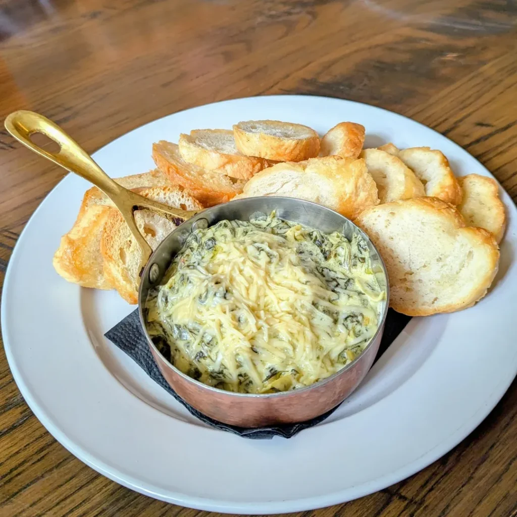 Mini Spinach and Artichoke Dip Cups topped with cheese and herbs on a platter.