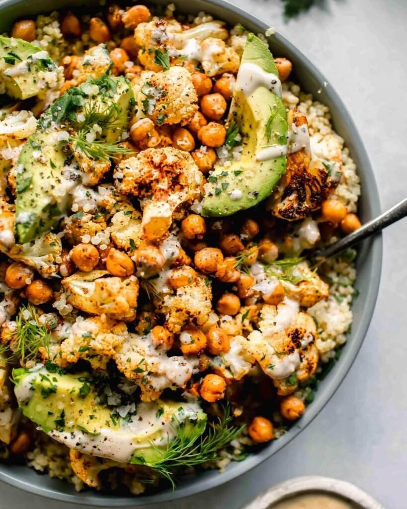 8 Meatless Monday Recipes To Try Tonight 7 A colorful bowl filled with quinoa, chickpeas, fresh vegetables, and a creamy sauce.