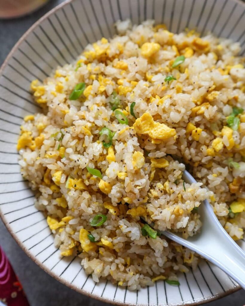 A bowl of egg fried rice topped with green onions