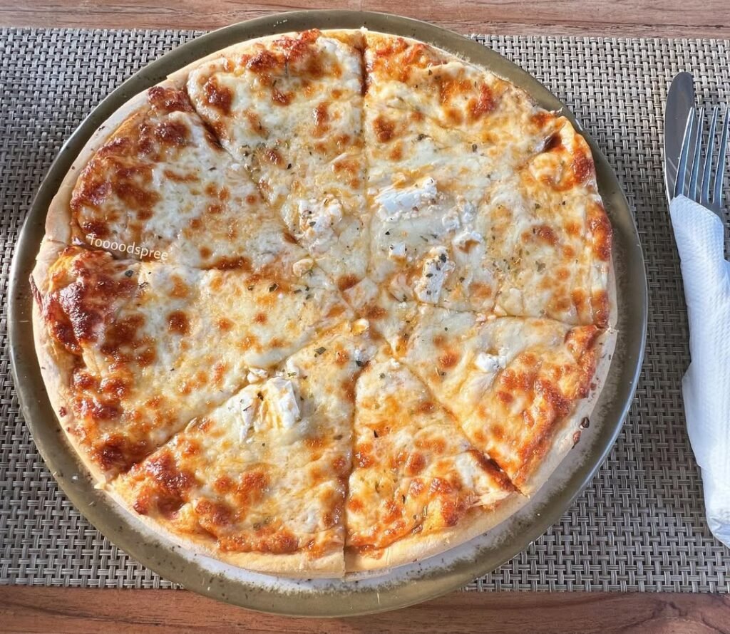 A delicious Four Cheese pizza with mozzarella, blue cheese, ricotta, and cheddar, garnished with fresh herbs.