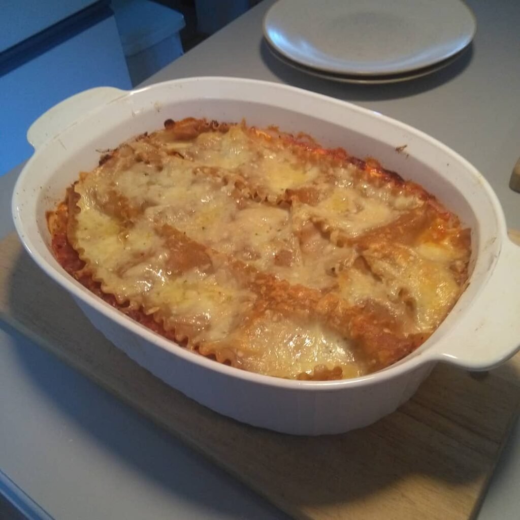 A delicious slice of vegetable lasagna with spinach and ricotta, garnished with fresh basil, surrounded by colorful vegetables.