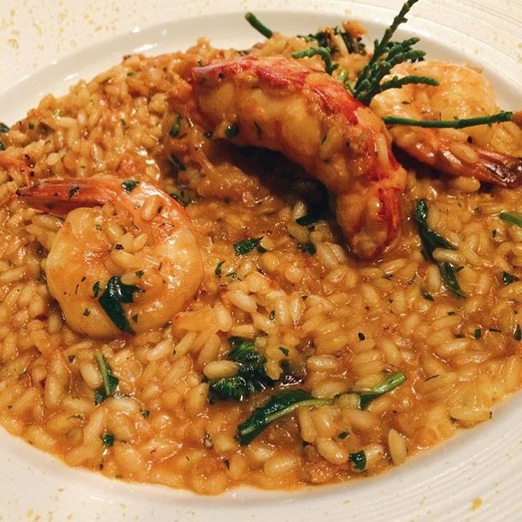 10 Lobster Dinner Recipes For A Taste Of Luxury 9 A plate of lobster risotto garnished with lobster claws and fresh herbs.