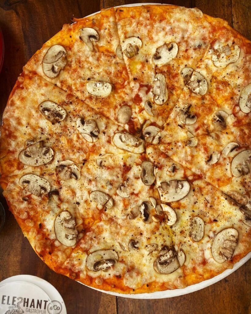 A pizza topped with fresh mushrooms and drizzled with truffle oil, garnished with parsley.