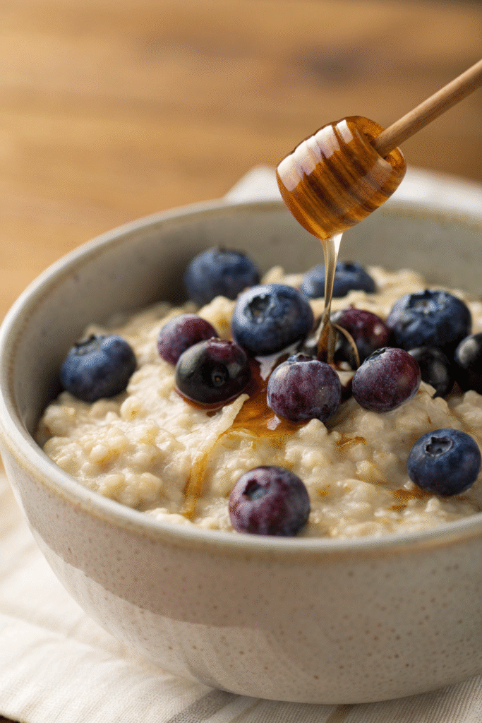A bowl of oatmeal topped with fresh blueberries, surrounded by more blueberries.