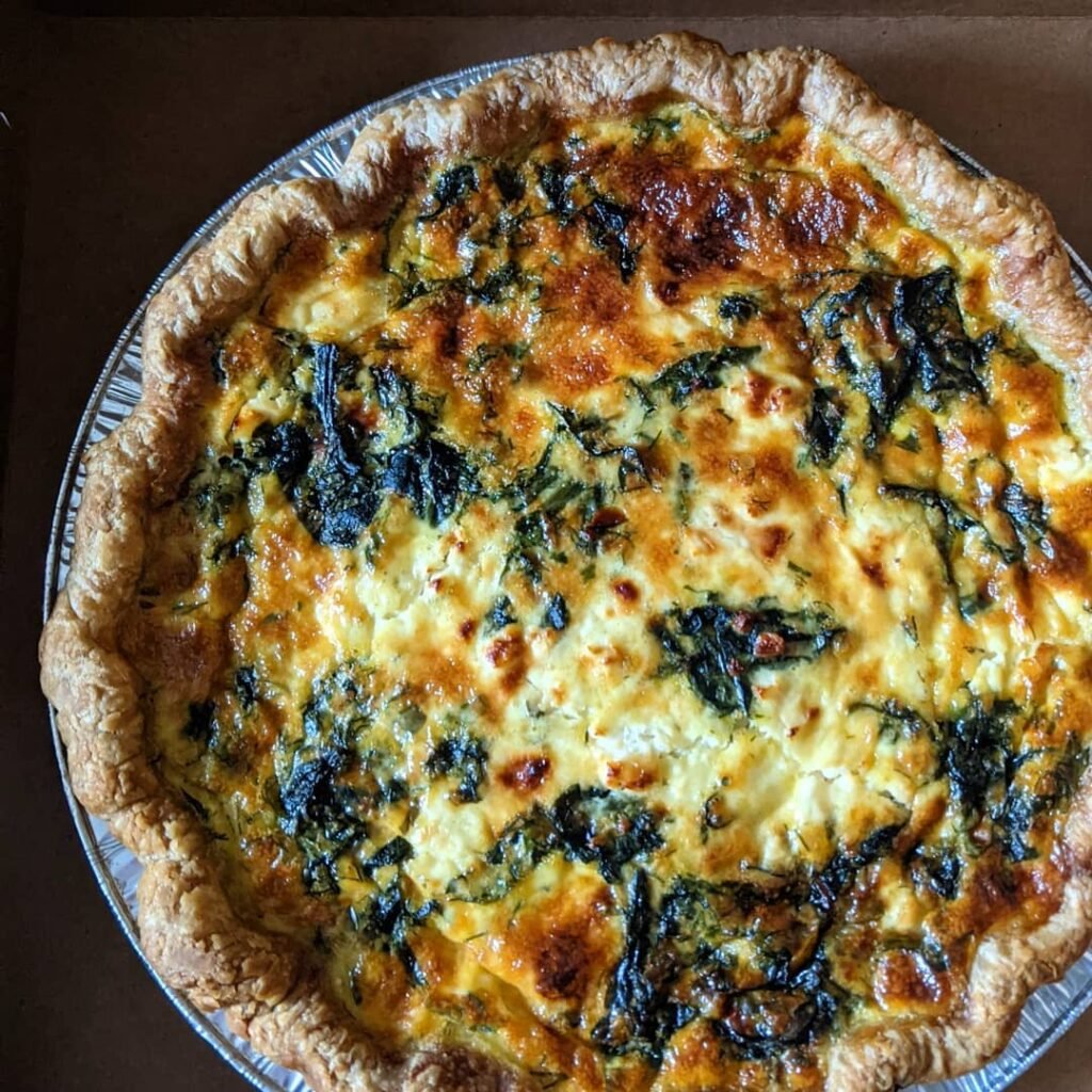 An assortment of mini quiches in pastry shells, featuring colorful fillings and garnished with herbs.