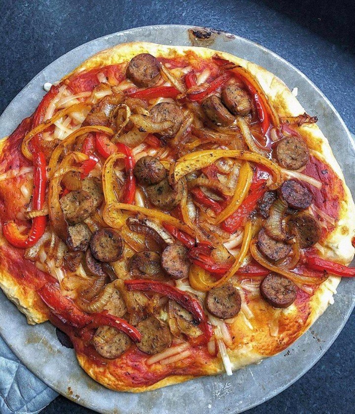 A delicious pizza topped with sausage, colorful bell peppers, and fresh parsley.