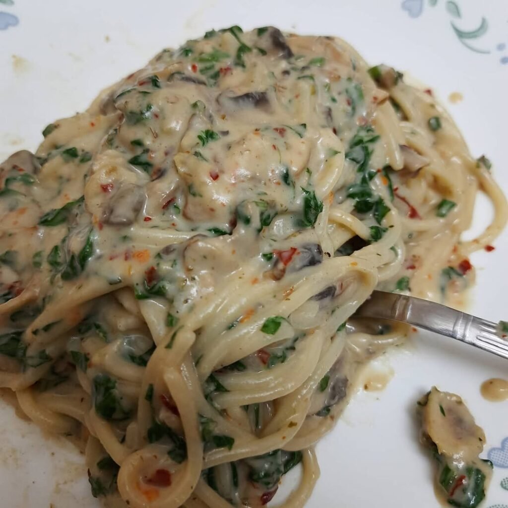 8 Meatless Monday Recipes To Try Tonight 3 A plate of creamy spinach and mushroom pasta garnished with basil and Parmesan cheese.