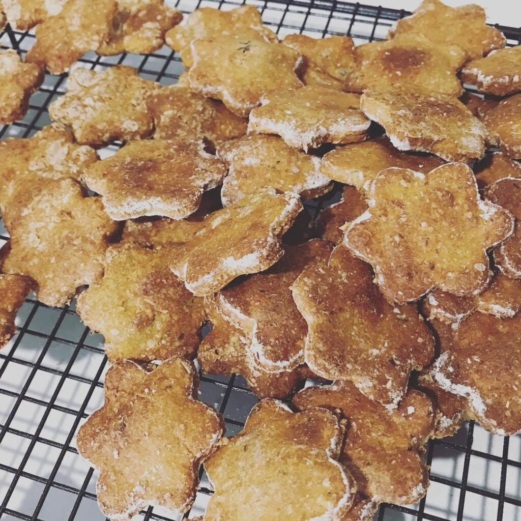 A happy dog with sweet potato and chicken jerky treats on a wooden table.