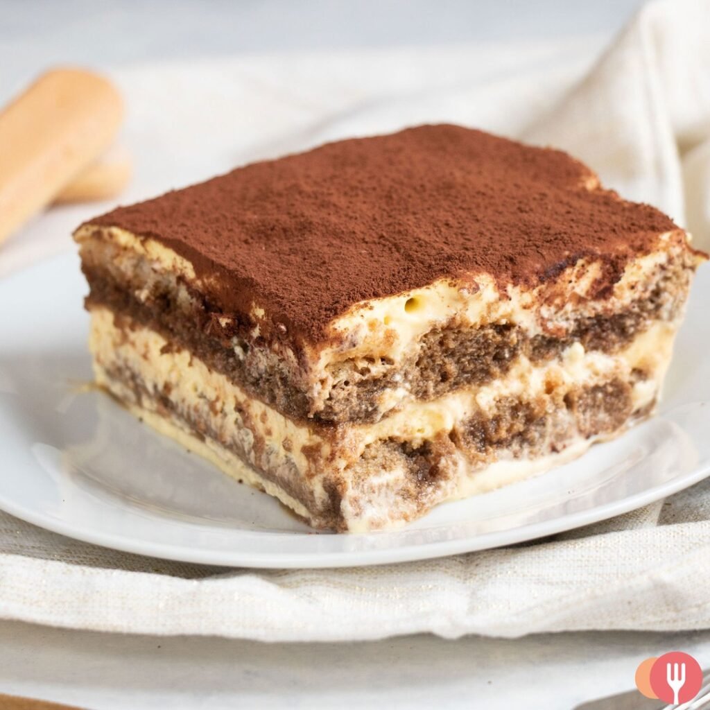 12 Delicious Birthday Dinner Recipes You’ll Love 10 A slice of classic Italian tiramisu dusted with cocoa powder on a decorative plate.