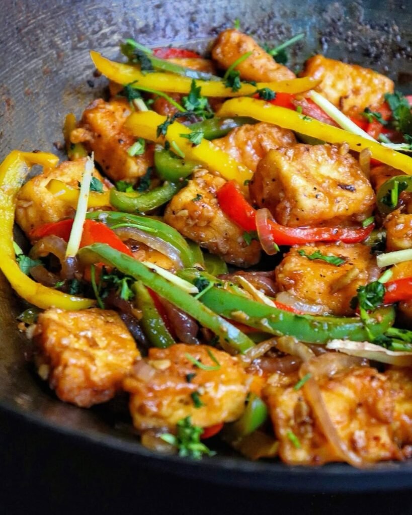 A colorful bowl of vegetable stir-fry with tofu, featuring bell peppers and leafy greens.