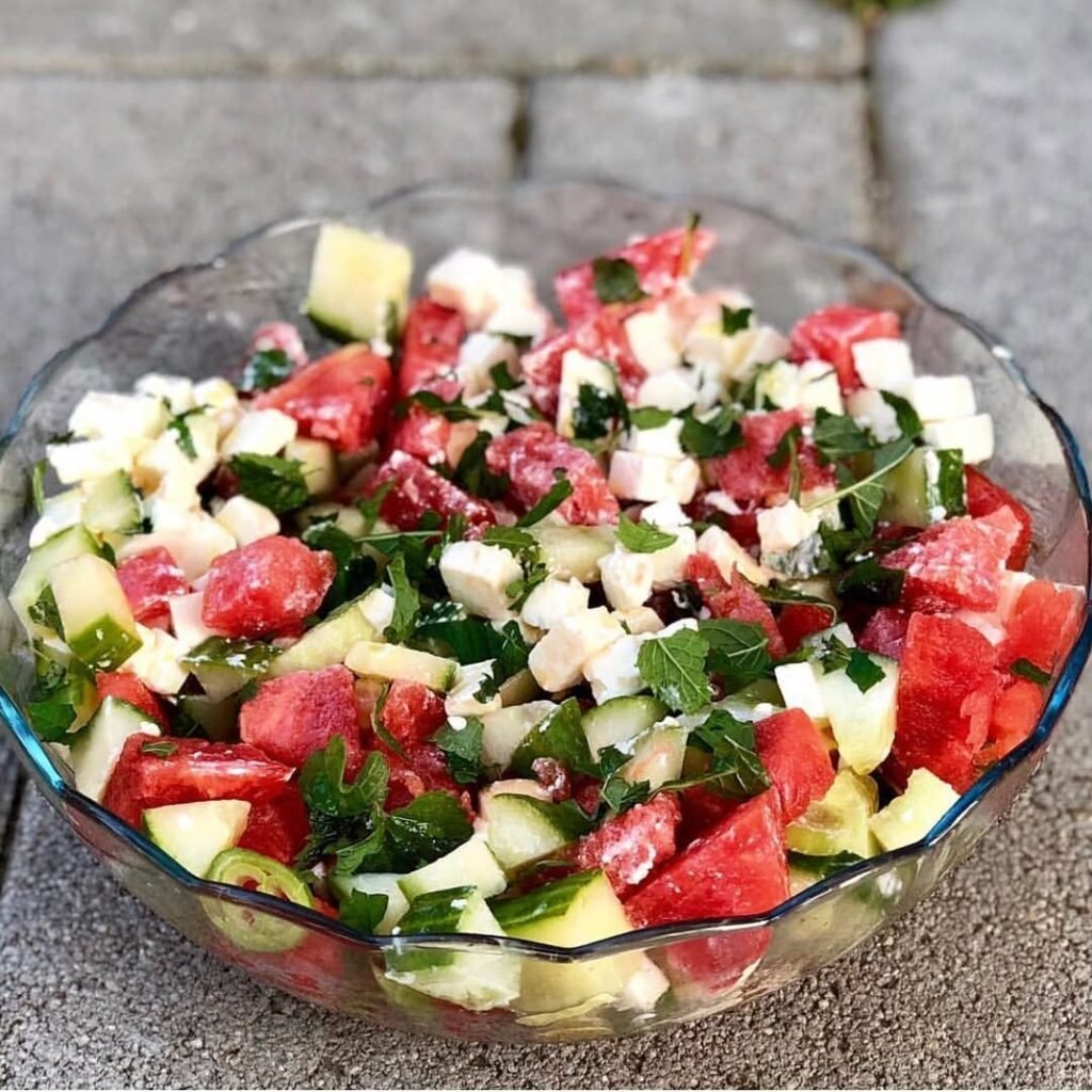 A bowl of watermelon feta salad topped with mint leaves.