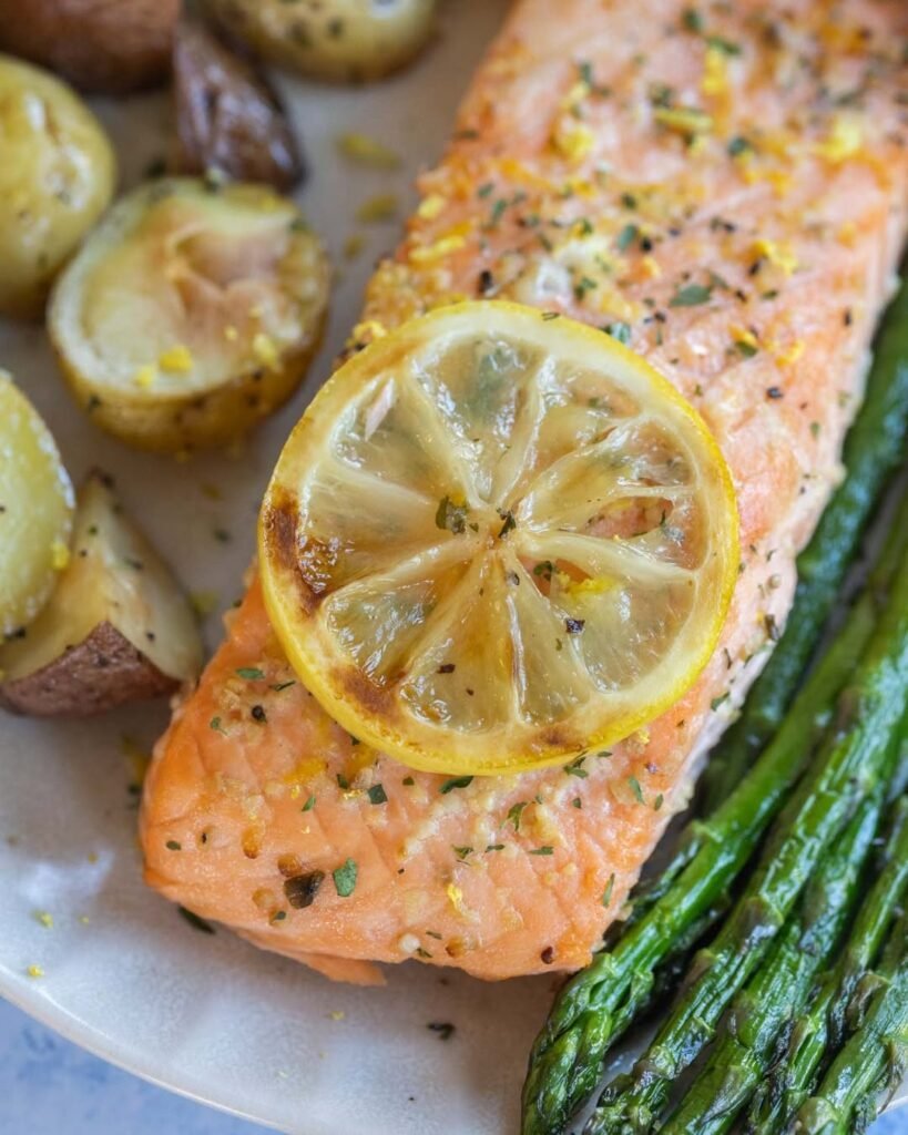 A plate of lemon garlic salmon with asparagus and lemon slices.