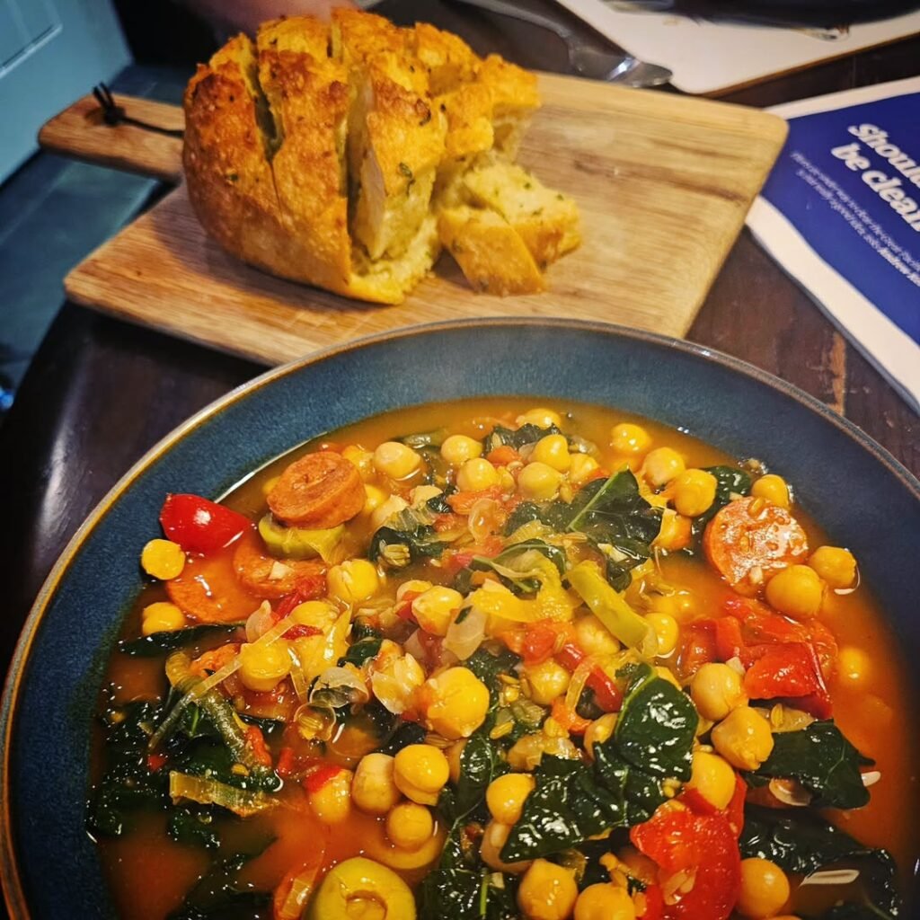 A hearty bowl of spicy chorizo and chickpea stew garnished with parsley.