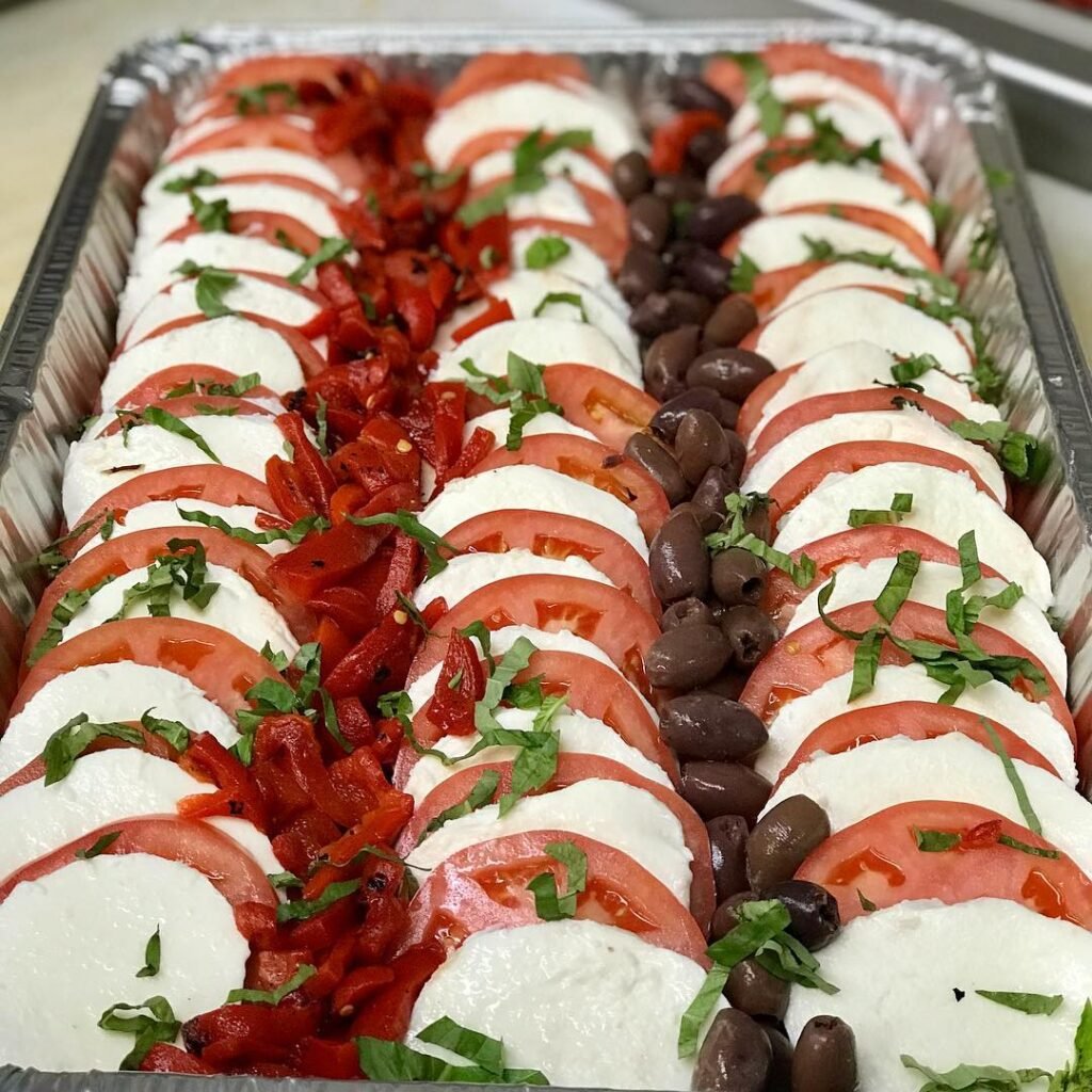 A vibrant Mozzarella Caprese Salad with slices of mozzarella, tomatoes, and fresh basil drizzled with balsamic glaze.