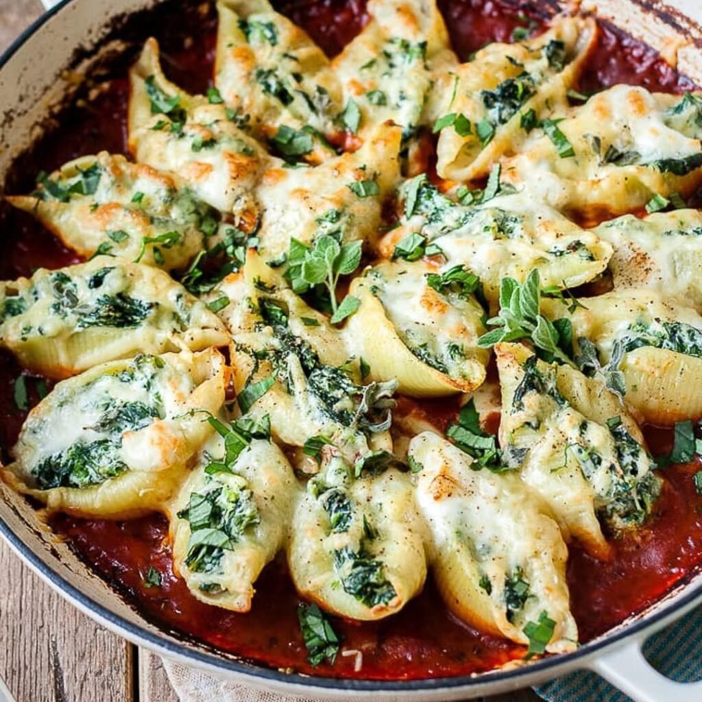 A plate of mozzarella and spinach stuffed shells topped with marinara sauce and sprinkled with cheese.